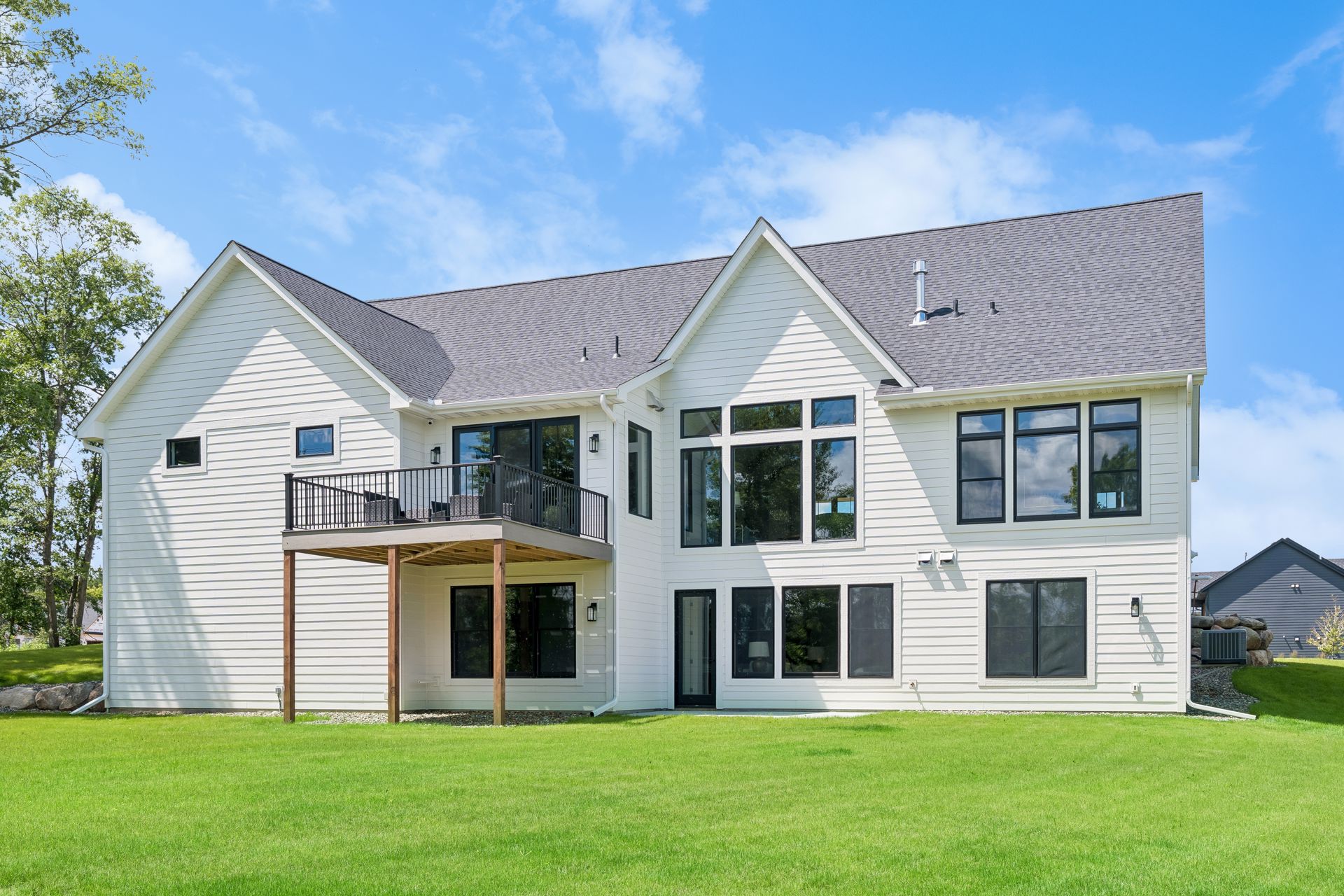 Rear exterior of luxury custom home with upper deck and large windows